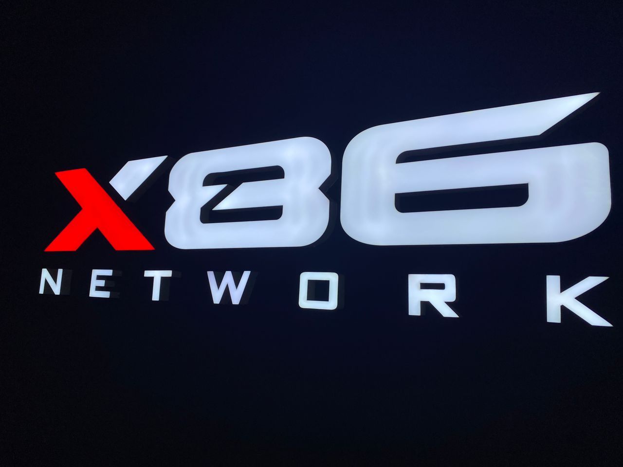 Illuminated X86 Network logo on the office wall